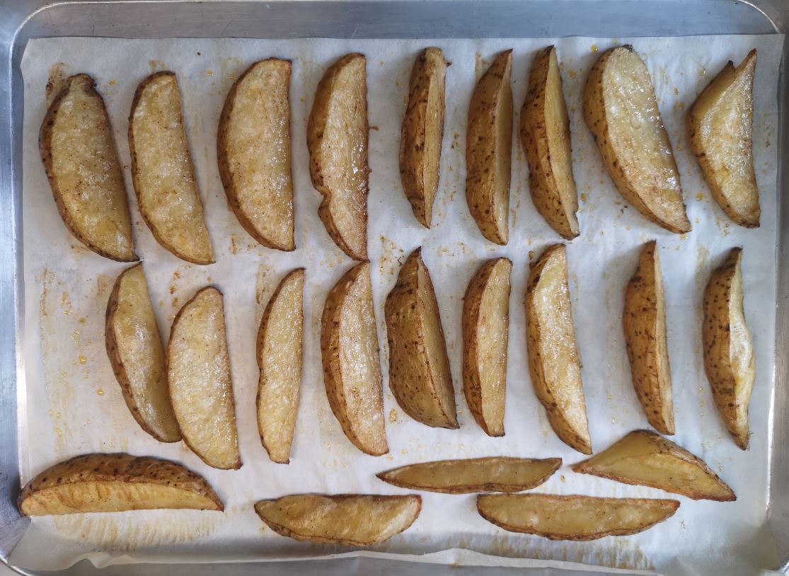 Spaced out potato wedges on the baking sheet